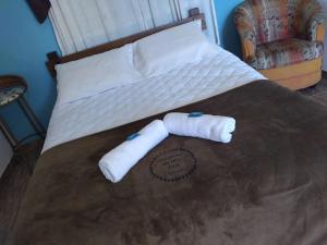 Una cama con dos toallas y una silla. en Pousada Cantinho da Mi & Teco, en Campos do Jordão