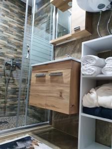 a bathroom with a shower and a wooden cabinet with a glass door at Apartmani Parice in Novi Pazar