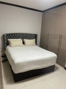Bett mit weißer Bettwäsche und Kissen in einem Zimmer in der Unterkunft 2Bedroom Luxury hotel apartment Fourways in Johannesburg