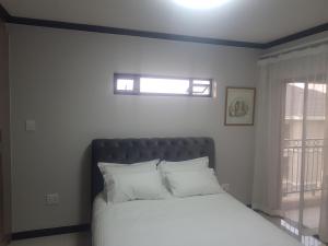um quarto com uma cama com almofadas brancas e uma janela em 2Bedroom Luxury hotel apartment Fourways em Joanesburgo