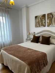 リャネスにあるApartamento La Muyerinaのベッドルーム1室(大型ベッド1台付)が備わります。壁には絵画2点が飾られています。