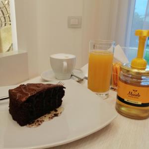 un pezzo di torta al cioccolato su un piatto con un bicchiere di succo d'arancia di Madì Paestum B&B - Bed & Breakfast a Paestum