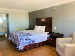 Habitación de hotel con cama y silla en Budget inn and suites, en Crowley