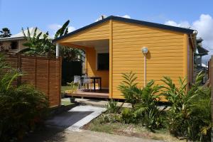 Bungalow Harmony في Baie Mahault: منزل صغير أصفر في حديقة