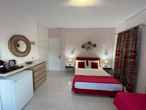 a bedroom with a red and white bed and a kitchen at Meltemi in Kamares