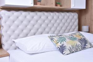 a white tufted bed with a pillow on it at Frajla in Novi Sad