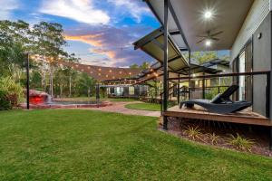 een huis met een schommel op een veranda met een tuin bij 'Tropical Oasis - Darwin NT in Humpty Doo