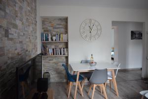 a dining room with a table and chairs and a clock at Superbe T3 classé 3 étoiles Chez Cathy et Frank situé en plein centre de Gérardmer in Gérardmer