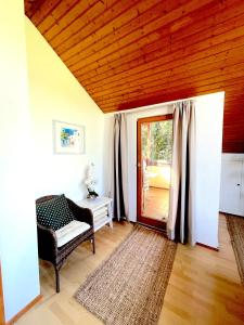 uma sala de estar com uma cadeira e uma porta de vidro deslizante em FeWo Natur & Entspannung am Bodensee em Langenargen