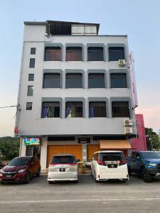 two cars parked in a parking lot in front of a building at 61 Hotel in Gua Musang