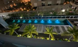 Apartamento inteiro para hospedagem في ساو باولو: مسبح فيه نخل امام مبنى
