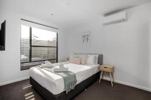 Habitación blanca con cama y ventana en Wattle Beachside Apartment, en McCrae