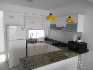 eine Küche mit weißen Schränken und einem weißen Kühlschrank in der Unterkunft Departamento en Punta Hermosa con Vista al Mar in Punta Hermosa