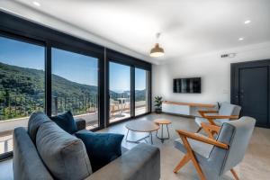a living room with a couch and tables and windows at Suites of happiness in Parga