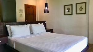 a bedroom with a large bed with white sheets and pillows at Villas by Eco Hotels Batangas in Mataasnakahoy