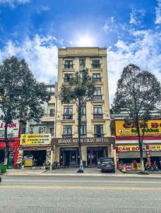 un gran edificio en una calle de la ciudad con árboles en Khách sạn Hoàng Minh Châu Mỹ Phước en Bến Cát