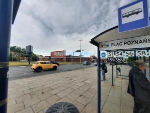 een bushalte met een gele auto die door een straat rijdt bij Central Apartment in Bydgoszcz