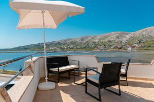 a patio with two chairs and a table and an umbrella at Apartment Lazić Pag by Pag tours in Pag