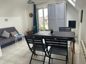 un soggiorno con tavolo, sedie e divano di Lebraz 3 Appartement a Saint-Lunaire