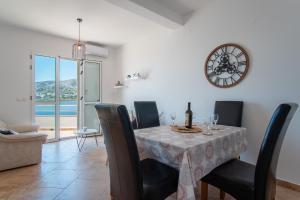 a dining room with a table with chairs and a clock at Apartment Lazić Pag by Pag tours in Pag