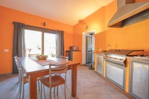 a kitchen with a table and chairs and a kitchen with orange walls at Villa Panoramica Porto Istana in Porto Istana