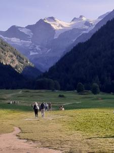 people walking down a dirt road in a field with mountains at appartamento signorile con giardino CIR 0097 in Aosta