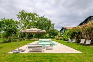a pool with a table and an umbrella and chairs at Séjour et Forme Route de Biarritz in Arbonne