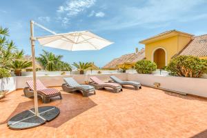 grupa krzeseł i parasol na patio w obiekcie Hanami Puerto Alto PA 7-7 w mieście Estepona