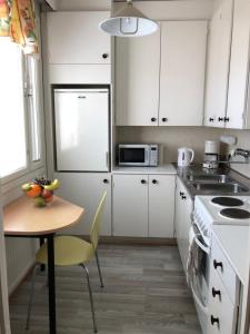 a kitchen with white cabinets and a table and a refrigerator at Lovely apartment within walking distance -centre in Pori