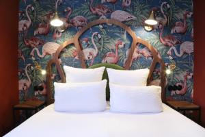 un letto con cuscini bianchi e carta da parati con fenicotteri di Hotel André Latin a Parigi