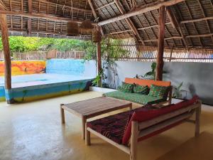 Habitación con mesa, banco y piscina en Jambiani Guest Lodge LITHAM en Kidenga
