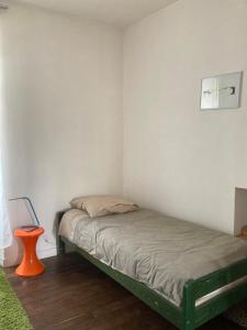 ドゥアルヌネにあるT2 Quartier du Rosmeurの小さなベッドルーム(ベッド1台、オレンジのスツール付)