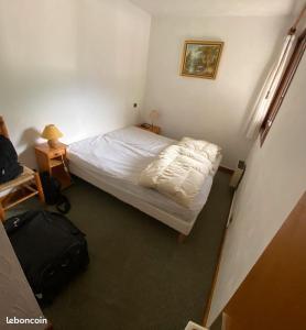 プラーズ・シュル・アルリーにあるLe Clos d'Arlyの小さなベッドルーム(ベッド1台、スーツケース付)