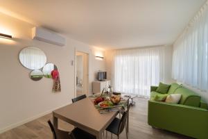a living room with a table and a green couch at Zero5.Zero5 in Lignano Sabbiadoro