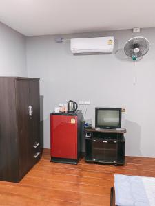 a room with a television and a red refrigerator at NP โฮมสเตย์ นอนเต็นท์ติดแอร์ in Ban Kaeng Manao