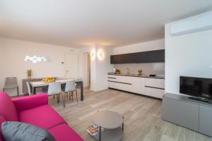 a living room with a pink couch and a kitchen at Zero5.Zero5 in Lignano Sabbiadoro