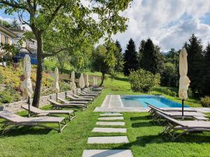 a row of chaise lounge chairs next to a swimming pool at Rota Apartments - Cà Guaccio in Rota d'Imagna