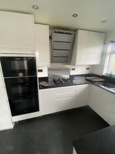 a kitchen with white cabinets and a black stove top oven at Theldon in Luton