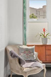 - une chaise avec un oreiller dans une chambre dotée d'une fenêtre dans l'établissement Stunning Victorian property near Canary Wharf!, à Londres