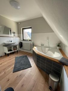a large bathroom with a large tub in the attic at Ferienhaus Esten's Eifelheimat Wehr Eifel in Wehr