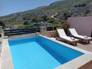 a swimming pool with two lounge chairs next to a house at Estia in Plátanos