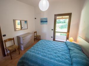 sypialnia z niebieskim łóżkiem, komodą i oknem w obiekcie Residence Cala Petralana w mieście Porto Pollo