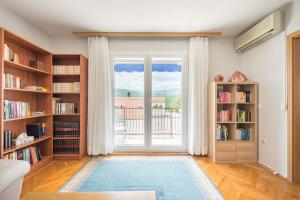 a living room with book shelves and a large window at Holiday home Goranka in Zmijavci