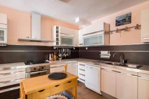 eine Küche mit weißen Schränken und einem Holztisch in der Unterkunft Holiday home Goranka in Zmijavci