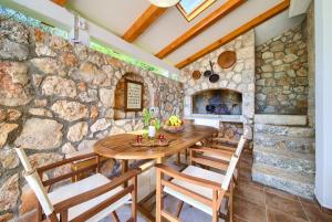 una cocina con paredes de piedra, mesa de madera y sillas en Villa Bodulova, en Polje