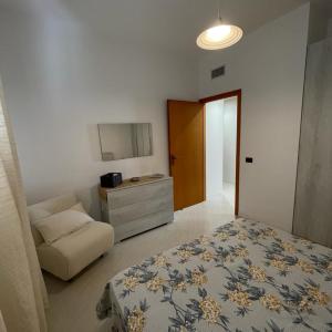 ein Schlafzimmer mit einem Bett, einem Stuhl und einer Kommode in der Unterkunft Zà Lisa in San Vito lo Capo