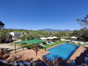 una casa y una piscina con sombrillas y sillas en Finca La Libertad en Coín