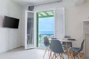a dining room with a table and a view of the ocean at Corali Suites Andros in Batsi