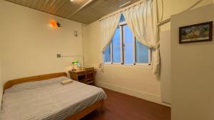 a bedroom with a bed and a large window at Tainan Guest House Hamuya in Tainan