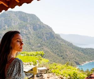 a woman standing on a balcony looking out at the ocean at Casa Di Pietra in Fethiye